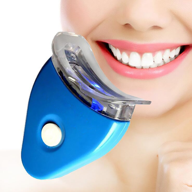 Person using teeth whitening gel with LED mouthpiece at home